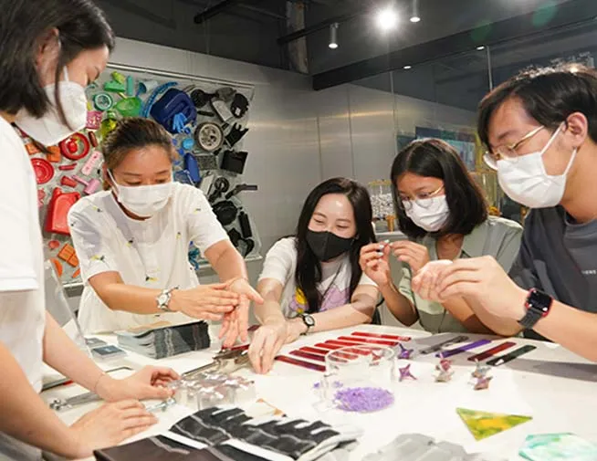 Group making objects from recycled plastic at a workshop table