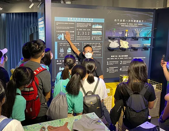 Students listening to a presenter at a recycling display