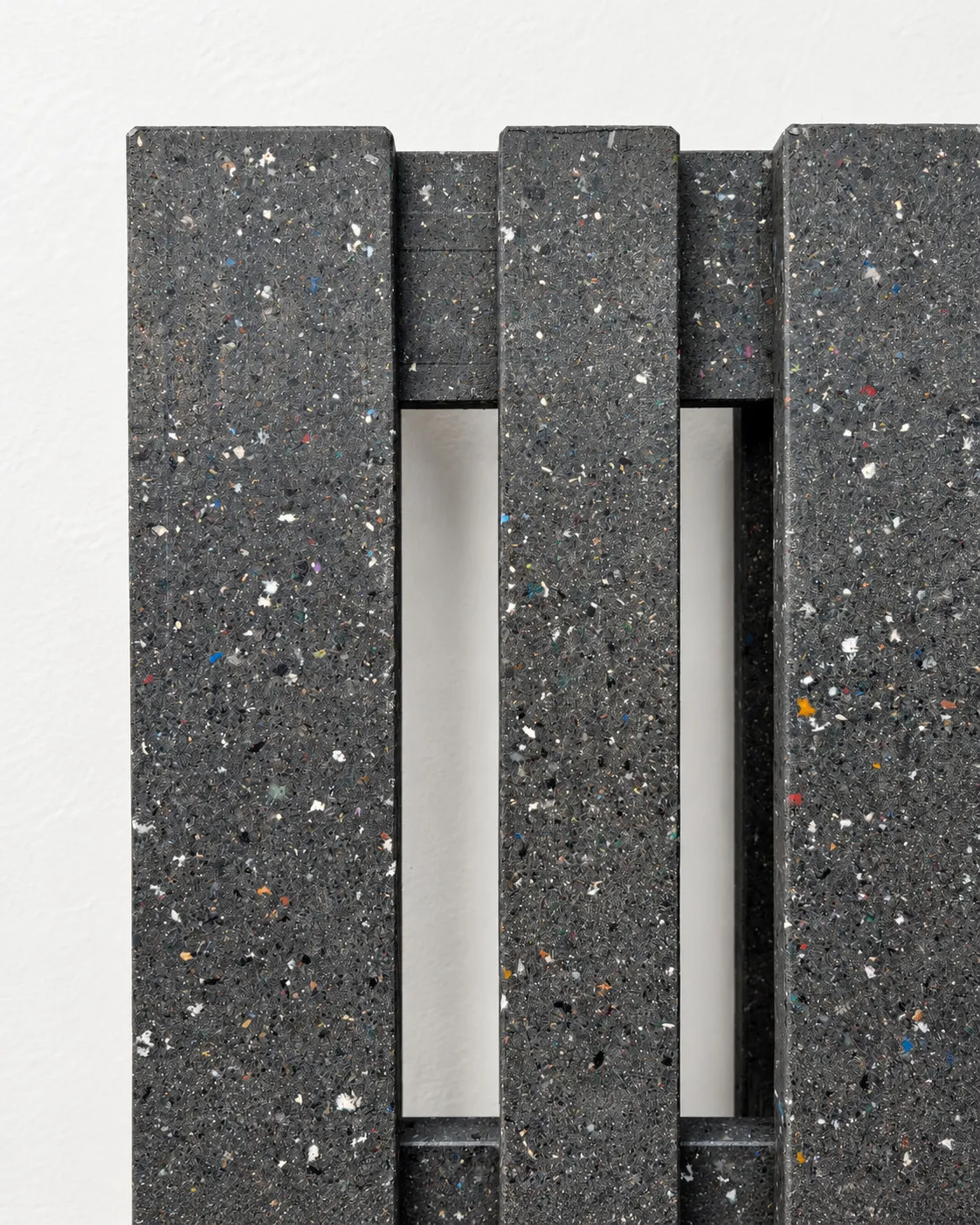 Close-up of the dark speckled composite boards and openings of a pallet prototype